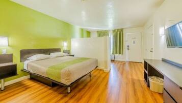 A hotel room with a bed, a desk, a television, and a door.