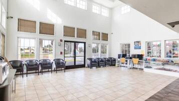 A spacious indoor area with a tiled floor, multiple windows, and a reception desk with chairs.