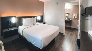 Ein Hotelzimmer mit Bett, Nachttischen, Fernseher und einem durchgehenden Türspalt sichtbaren Badezimmer.