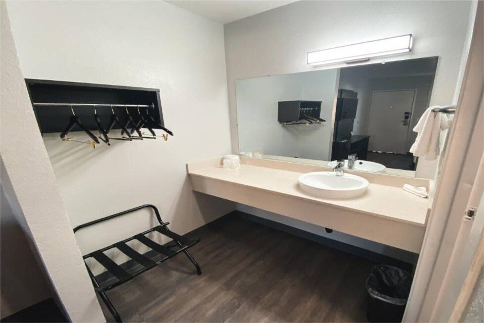 A small bathroom with a white sink, a mirror, and a black towel rack.