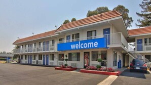 A motel with a 'welcome' sign, multiple balconies, and a parking area. - 2 Queen Beds|NS| Kitchen (West Sacramento)