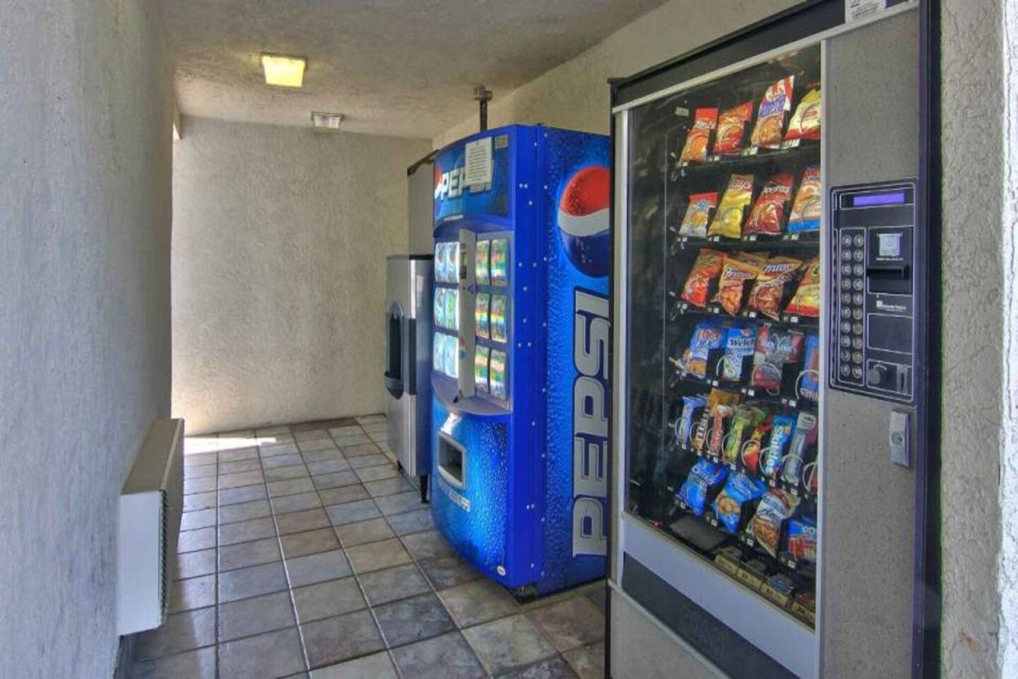 Alue, jossa on automaatti, jossa myydään Pepsi-tuotteita, sekä toinen automaatti, jossa myydään pikkupurtavaa.