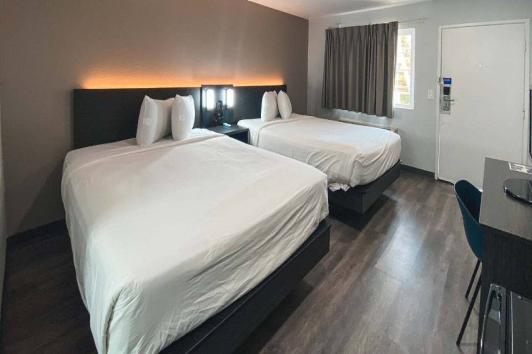 Ein Hotelzimmer mit zwei Betten, einem Schreibtisch und einem Stuhl.