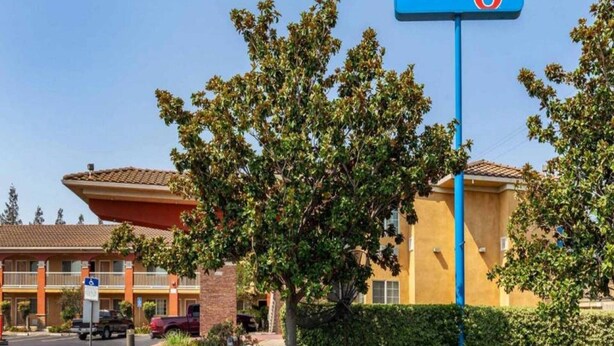 Ein Motel mit Schild, Parkplatz und einem Gebäude mit rotem Dach.