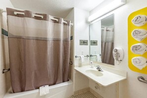 Un baño con cortina de ducha, lavabo, espejo y toallero con toallas.