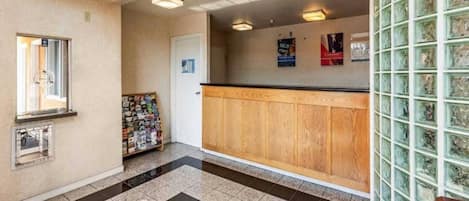A reception area with a wooden counter, a magazine rack, and a glass wall with a grid pattern.
