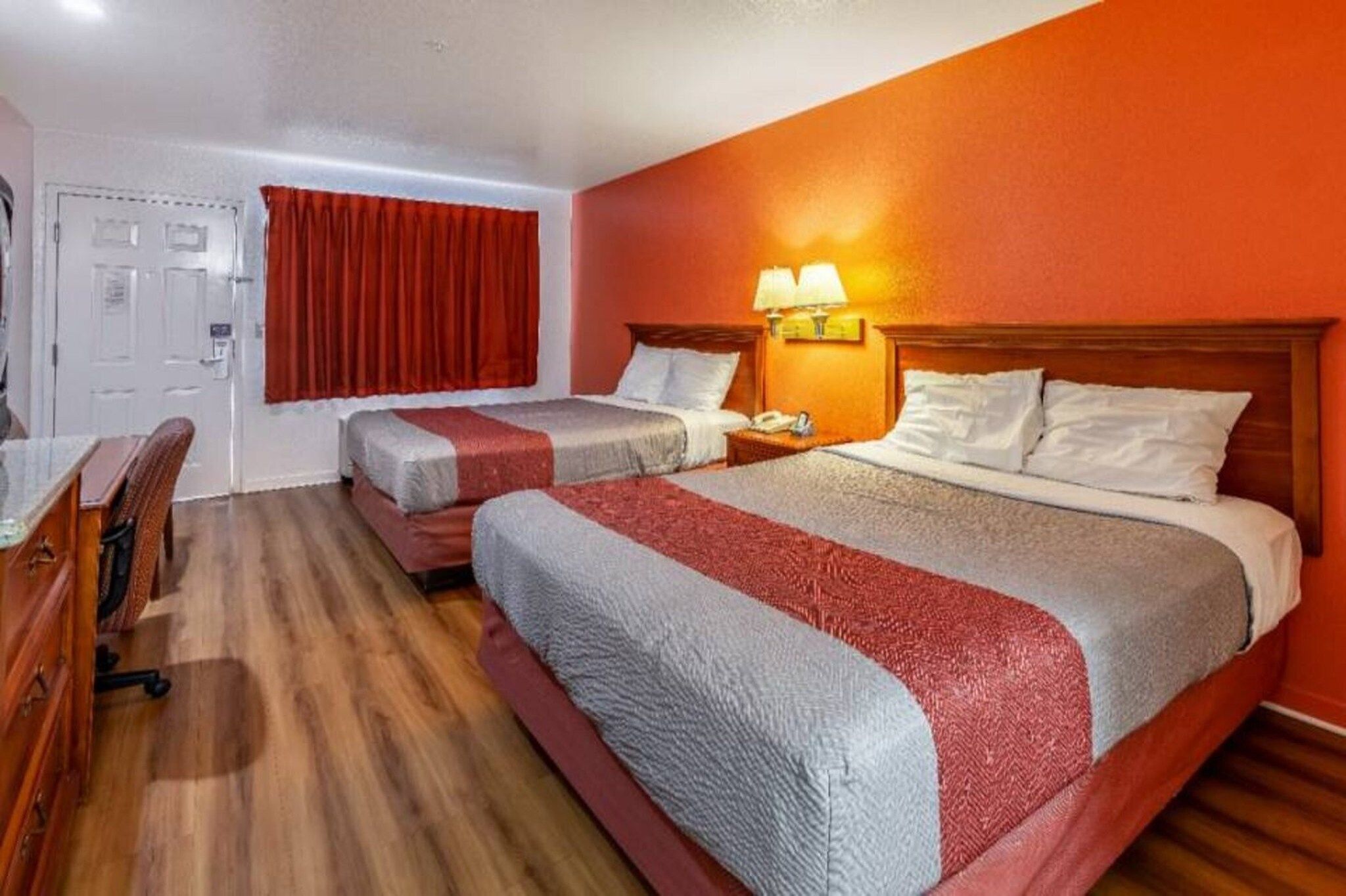 Ein Hotelzimmer mit zwei Betten, einem Schreibtisch und einem Stuhl.