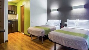 Ett hotellrum med två sängar, ett litet kök och en grön vägg.