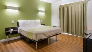 Een hotelkamer met een bed, nachtkastje en gordijn.