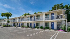 Een motel met meerdere verdiepingen, een parkeerplaats en een heldere lucht.