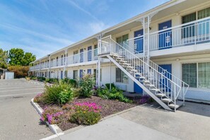 A motel with a central staircase, multiple balconies, and a landscaped garden area.