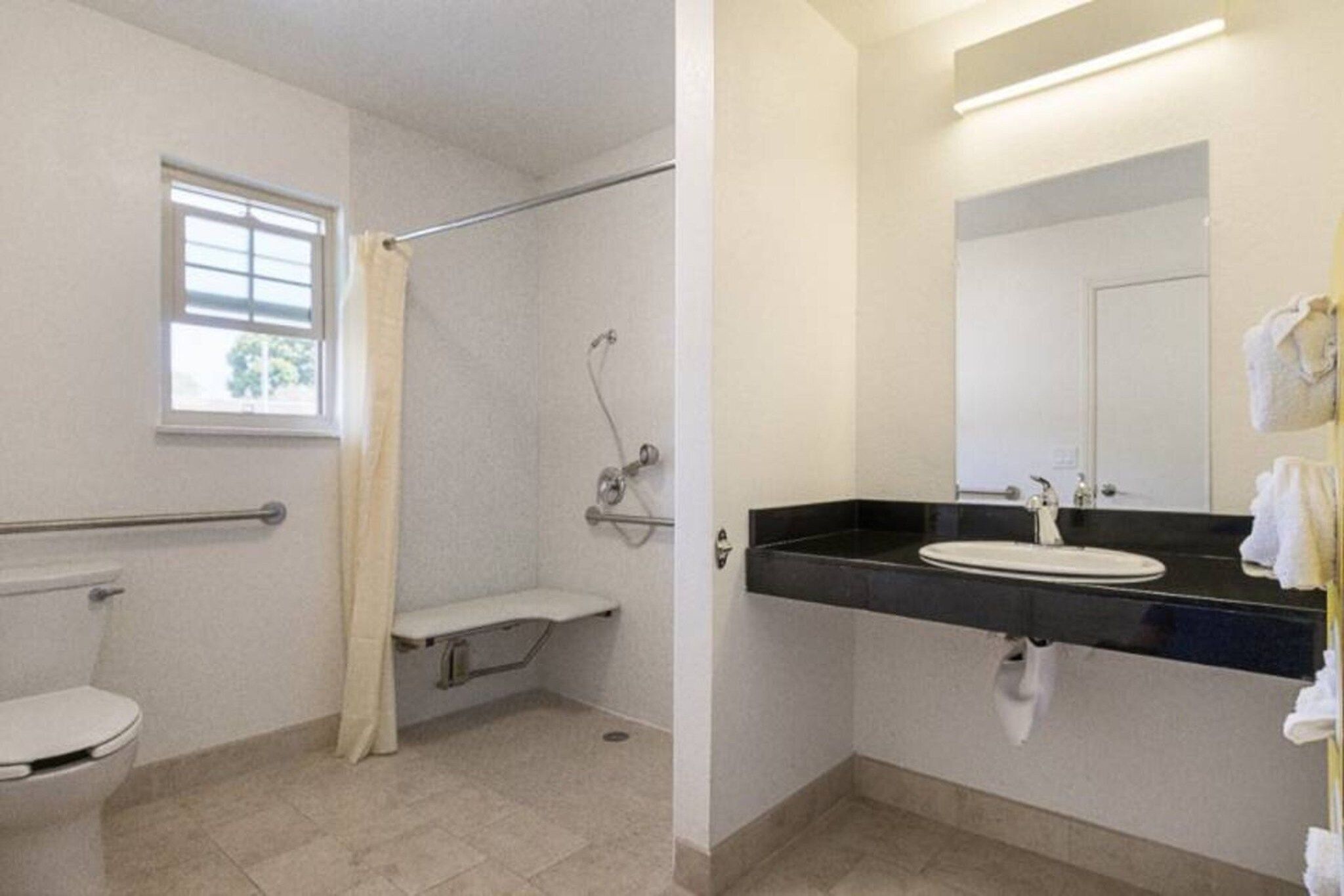 A bathroom with a toilet, shower, and sink.
