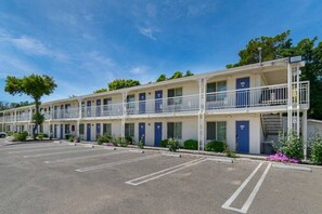 Un motel de varios pisos, estacionamiento y cielo despejado.