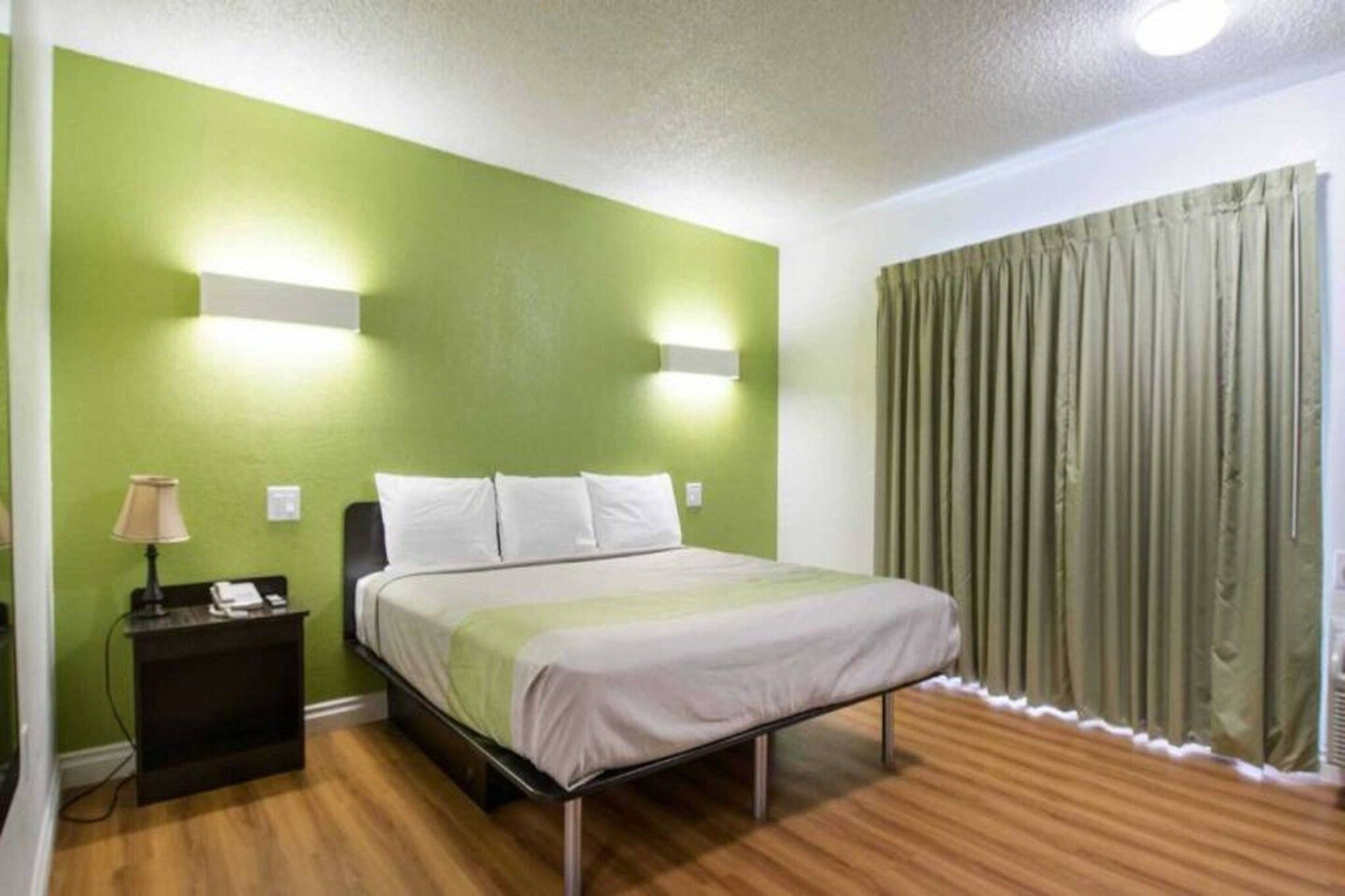 A hotel room with a bed, bedside lamp, and curtains.