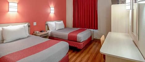 Une chambre d’hôtel avec deux lits, un bureau et une télévision.
