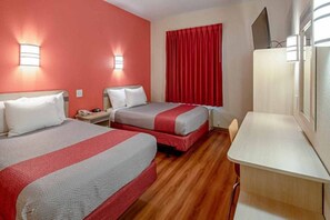 Habitación de hotel con dos camas, un escritorio y televisión.