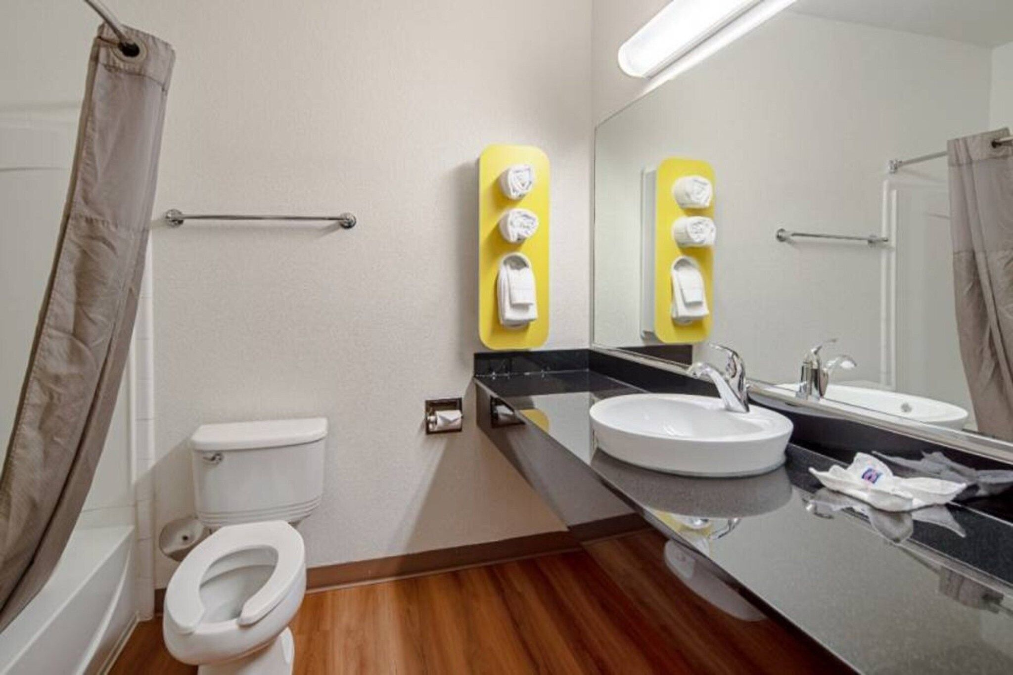 A bathroom with a toilet, sink, and mirror.