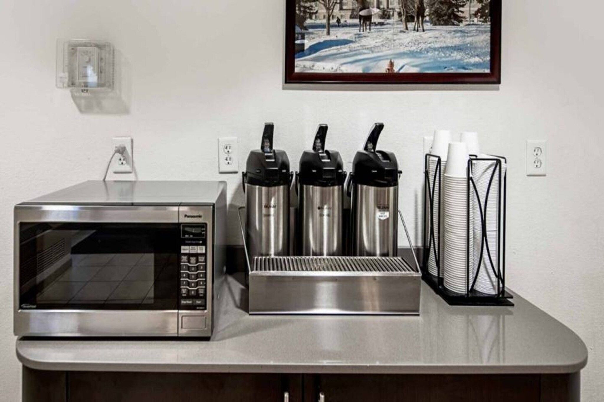 Una kitchenette con microondas, tres hervidores eléctricos y una cafetera.