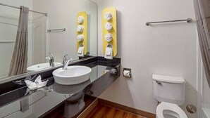 Un baño moderno con lavamanos, espejo, inodoro y dispensadores de toallas.