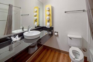 Un baño moderno con lavamanos, espejo, inodoro y dispensadores de toallas.