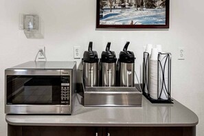 Een kitchenette met een magnetron, drie elektrische waterkokers en een koffieapparaat.