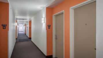 Un pasillo de hotel con puertas numeradas 214 y 213, pisos alfombrados y paredes blancas.