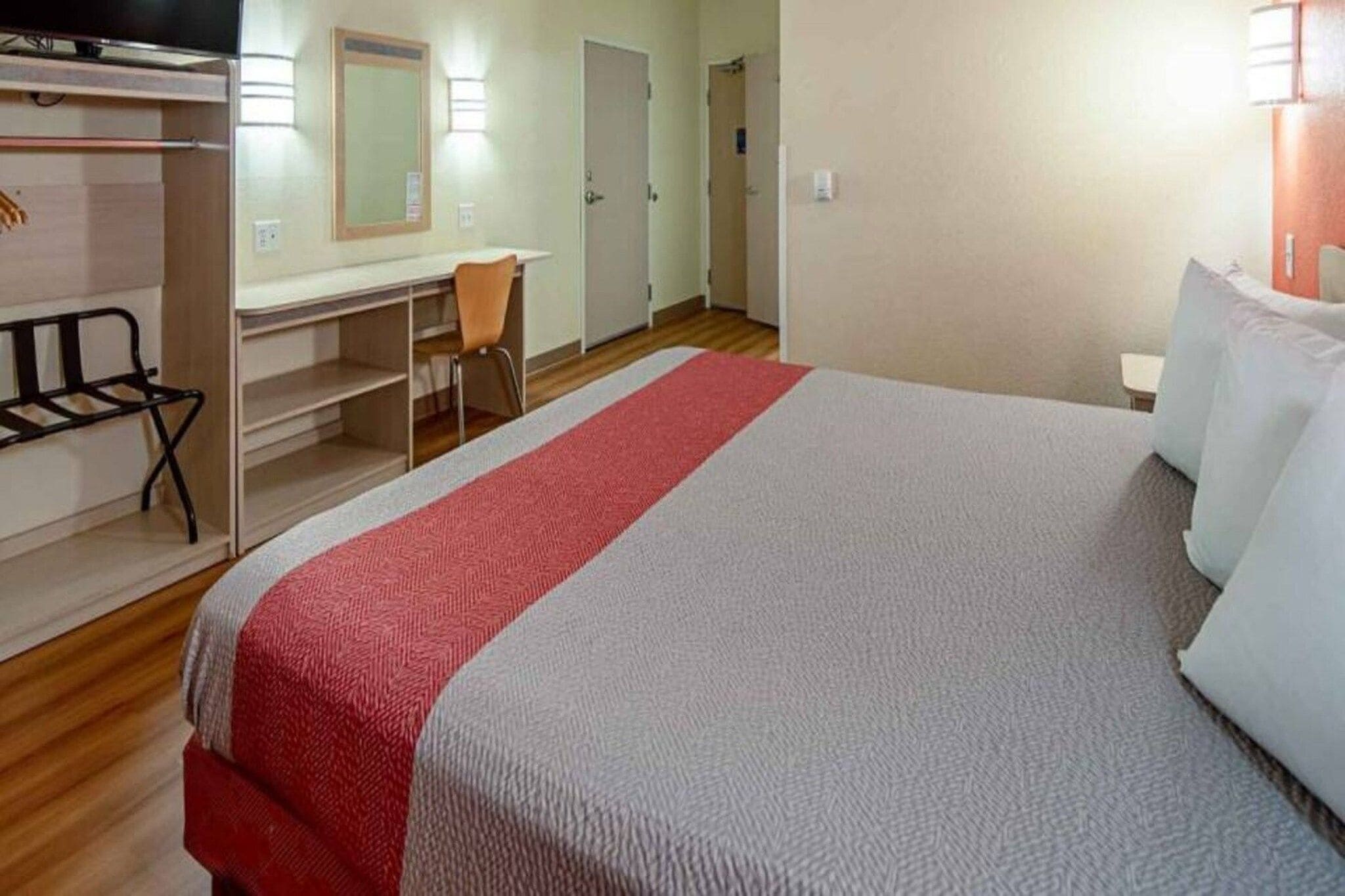 Une chambre d’hôtel avec un lit, un bureau, une chaise et un téléviseur.