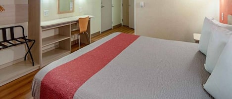 Une chambre d’hôtel avec un lit, un bureau, une chaise et un téléviseur.