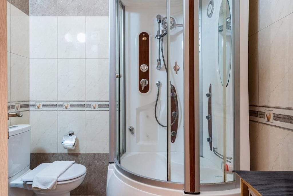 Un baño moderno con ducha acristalada, inodoro y lavamanos.
