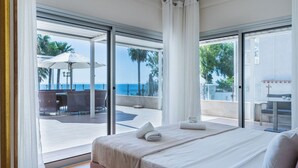 Ein Hotelzimmer mit Bett, Meerblick und einer Sitzgelegenheit im Freien mit Sonnenschirmen.