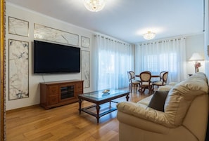 A living room with a flat-screen TV, wooden furniture, and marble wall art. - Beachfront 3BR Apartment with Sea Views (Ayios Tychonas)