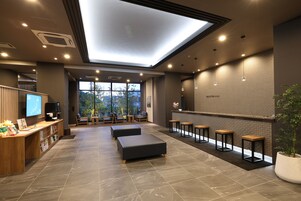 Vestíbulo moderno de hotel con mostrador de recepción, área de estar y un gran ventanal con vistas al exterior.