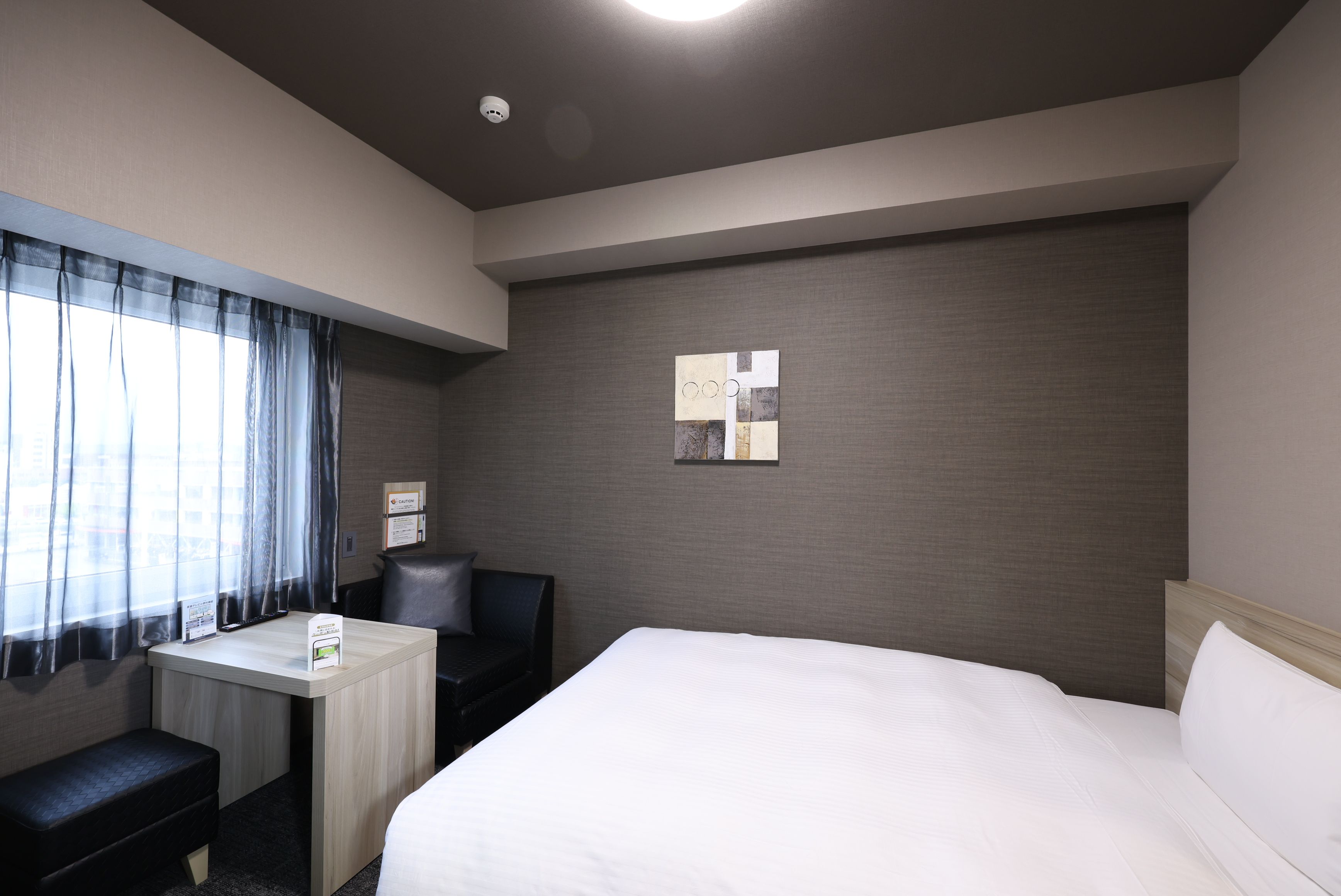 Una habitación de hotel con cama, escritorio, silla y una mesita.