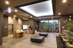 Un vestíbulo moderno con mostrador de recepción, zona de estar y un amplio ventanal con vistas al exterior.