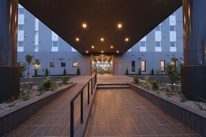 A modern hotel entrance with a covered walkway, tiled flooring, and a clear view of the building's facade. - HotelRouteInnKobesanda-ShinSandaEkimae- (Sanda)