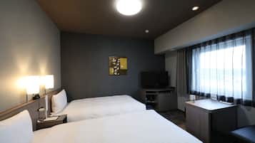 Habitación de hotel con dos camas, un escritorio, un televisor y una ventana con cortinas.