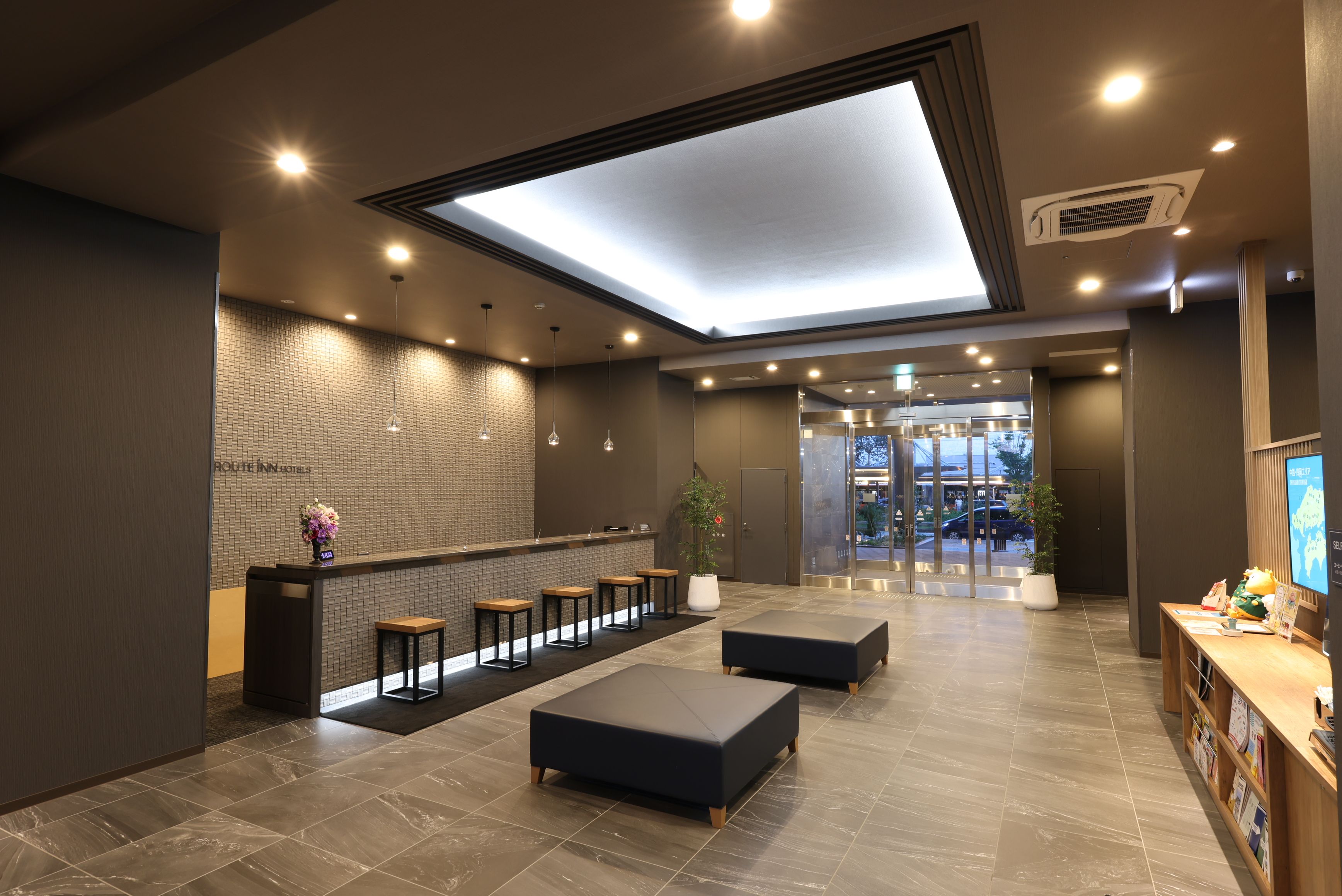Un moderno vestíbulo de hotel con mostrador de recepción, zona de estar y un amplio tragaluz.