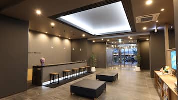 Un moderno vestíbulo de hotel con mostrador de recepción, zona de estar y un amplio tragaluz.