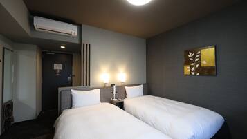 Ein Hotelzimmer mit zwei Betten, einer Wand-Klimaanlage und einem Gemälde.