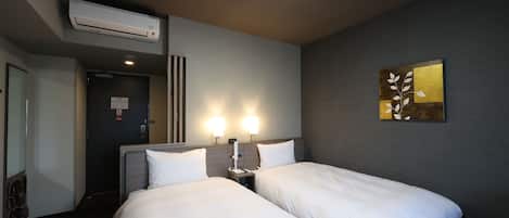 A hotel room with two beds, a wall-mounted air conditioner, and a painting.