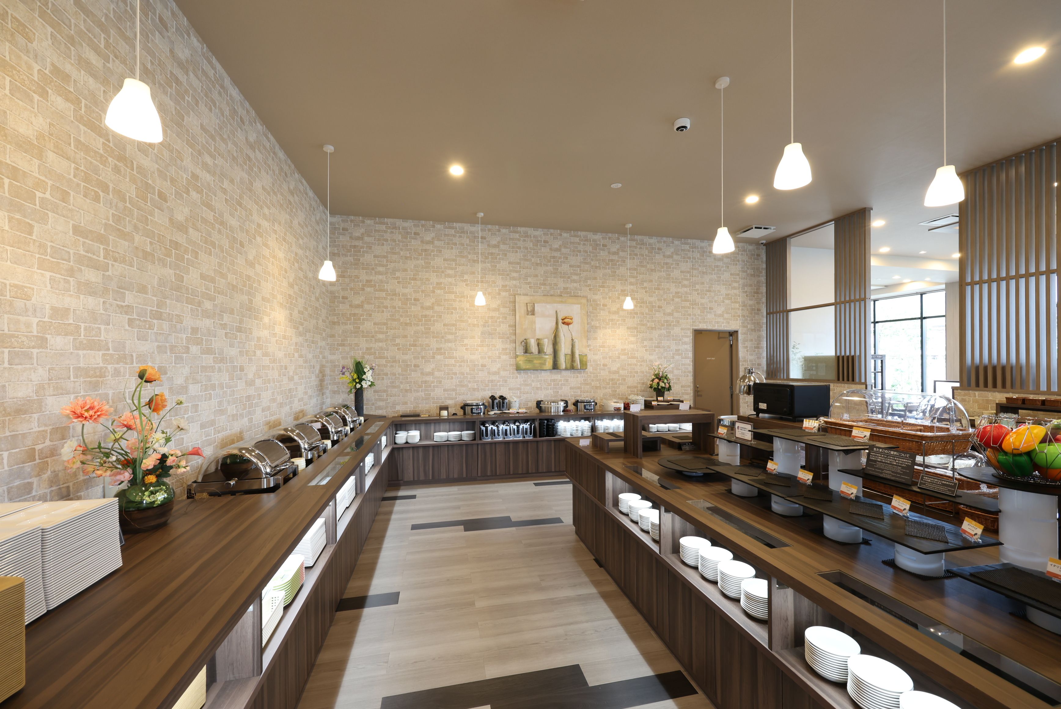 A modern hotel lobby with a brick wall, a reception desk, and a buffet area.