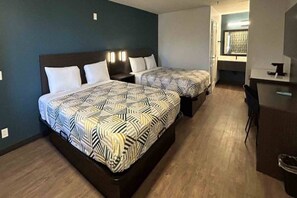 Habitación de hotel con dos camas, un escritorio y una silla.