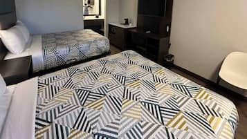 Una habitación de hotel con dos camas, un televisor, un escritorio y una silla.