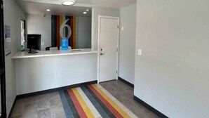 A hallway with a reception desk, a door, and a colorful striped floor. - 1 King Bed | Non-Smoking, Micfridge (Lake Elsinore)