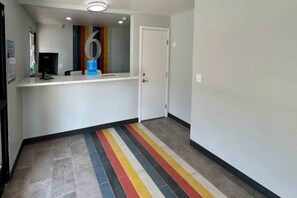Un couloir avec un comptoir d’accueil, une porte et un sol rayé aux couleurs vives.