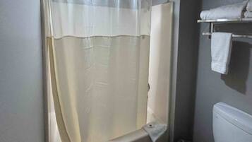 Un baño con cortina de ducha, toallero y una toalla, y un inodoro.