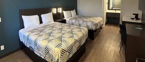 A hotel room with two beds, a desk, and a chair.