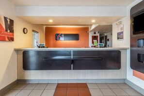 A reception desk with a digital clock, a sign with the number 6, and a tiled floor.