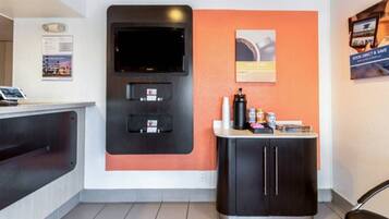Ein Empfangsbereich mit Flachbildfernseher, Selbstbedienungskiosk und Kaffeeautomat.