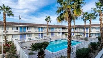 A motel with a swimming pool surrounded by palm trees.